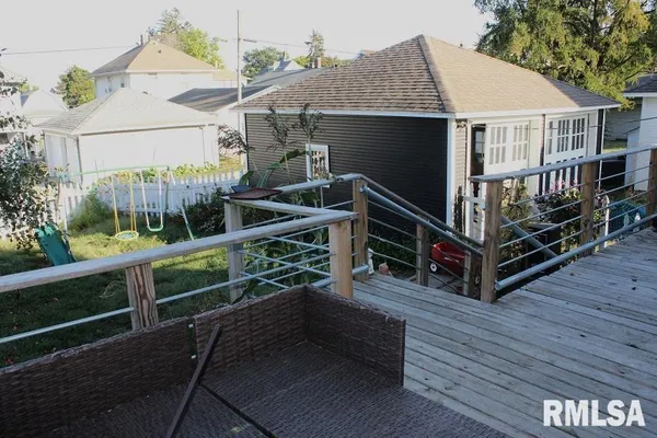 a view of house with a deck and a yard