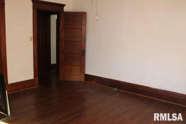 a view of an empty room with wooden floor and closet