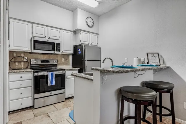 a kitchen with stainless steel appliances kitchen island a table chairs microwave and sink