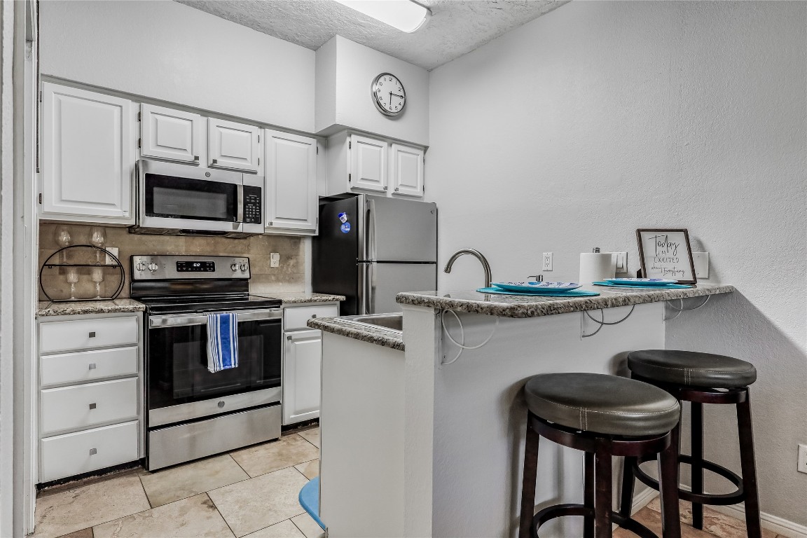 3404 American Drive, Unit 3300 Lago Vista, TX 78645 - Photo 4 of 39 a kitchen with stainless steel appliances kitchen island a table chairs microwave and sink