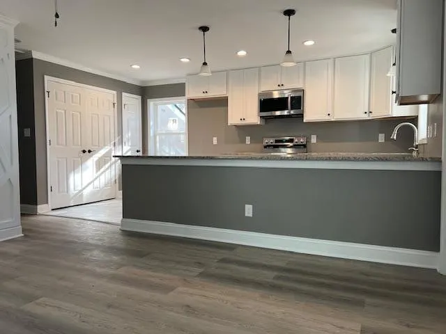 a view of kitchen with granite countertop stainless steel appliances and sink