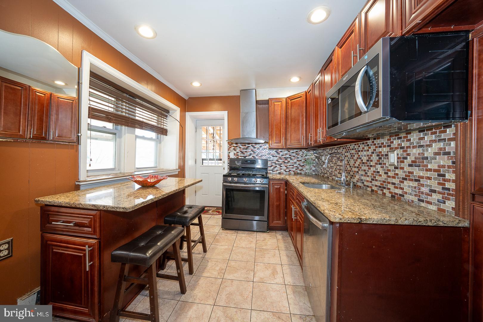136 Summit Avenue Upper Darby, PA 19082 - Photo 11 of 48 a kitchen with stainless steel appliances granite countertop a stove a sink and a microwave