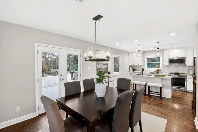 a view of a dining room and livingroom with furniture wooden floor a rug and a chandelier