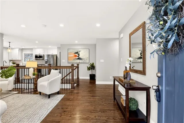 a living room with furniture kitchen view and a wooden floor