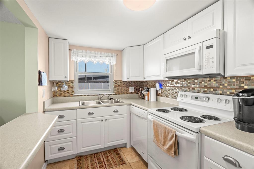 7701 Starkey Road, Unit 601 Seminole, FL 33777 - Photo 12 of 28 a kitchen with white cabinets sink and white appliances
