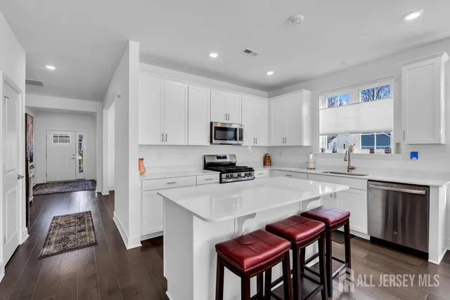 a kitchen with stainless steel appliances granite countertop a stove top oven a sink dishwasher and a refrigerator with wooden floor