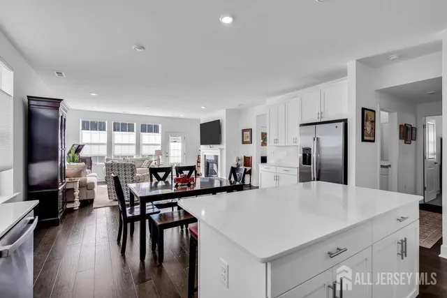 a kitchen with stainless steel appliances a dining table chairs a refrigerator and cabinets