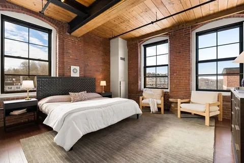 a bedroom with a large bed and windows