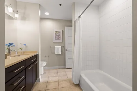 a bathroom with a granite countertop sink a toilet and shower