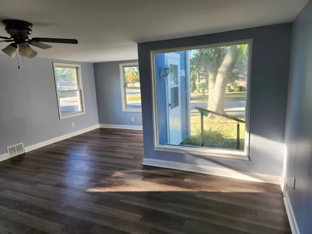 an empty room with wooden floor and windows