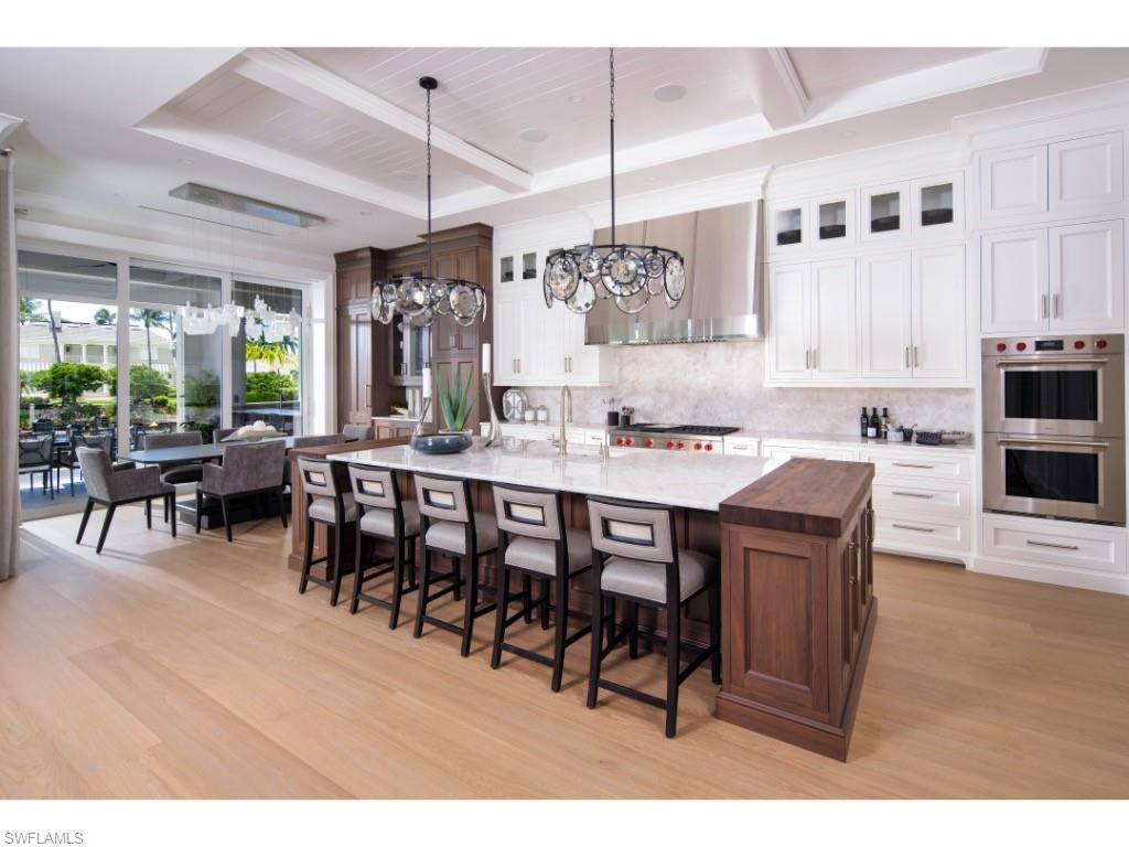 3200 Gin Lane Naples, FL 34102 - Photo 6 of 20 a open kitchen with stainless steel appliances granite countertop a stove a refrigerator a dining table and chairs with wooden floor