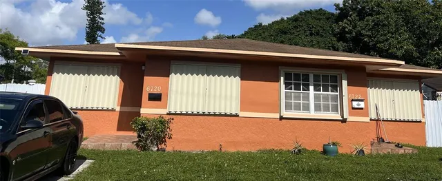 a view of a house with a large window and potted plants