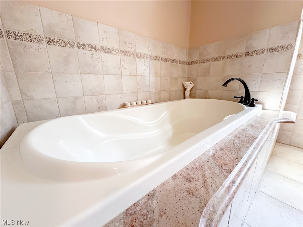 11911 County Line Road Chesterland, OH 44026 - Photo 34 of 49 Bathroom with tile walls, a bathing tub, and tile floors