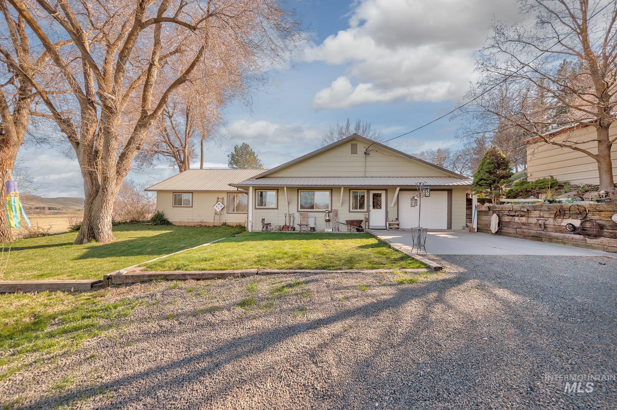 Bungalow-style house featuring concrete driveway, a garage, a front yard, covered porch, and a metal roof