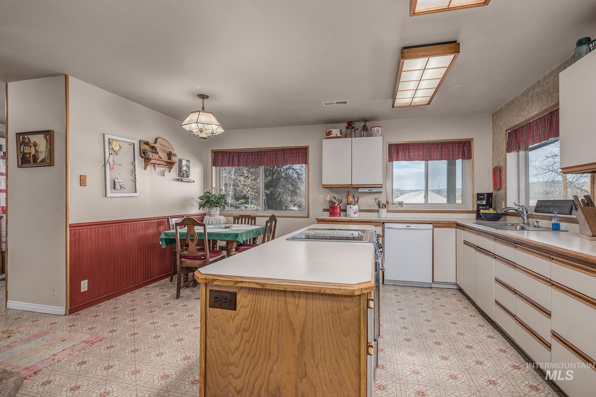 1365 Highway 95 Weiser, ID 83672 - Photo 6 of 34 Dual tone kitchen featuring light floors, a wainscoted wall, light countertops, dishwasher, and wood walls