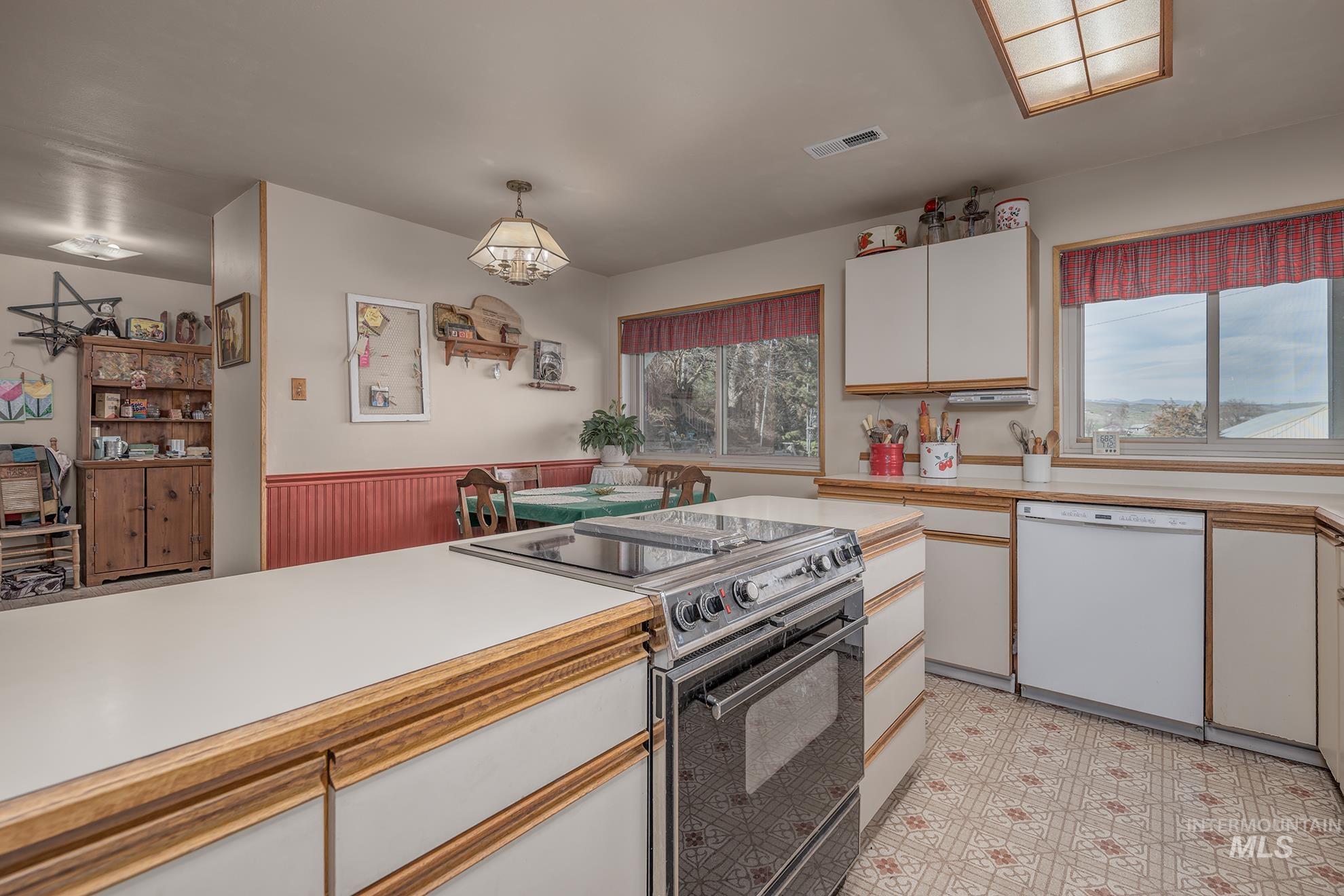 1365 Highway 95 Weiser, ID 83672 - Photo 7 of 34 Kitchen with black electric range, light countertops, two tone color scheme, white dishwasher, and decorative light fixtures