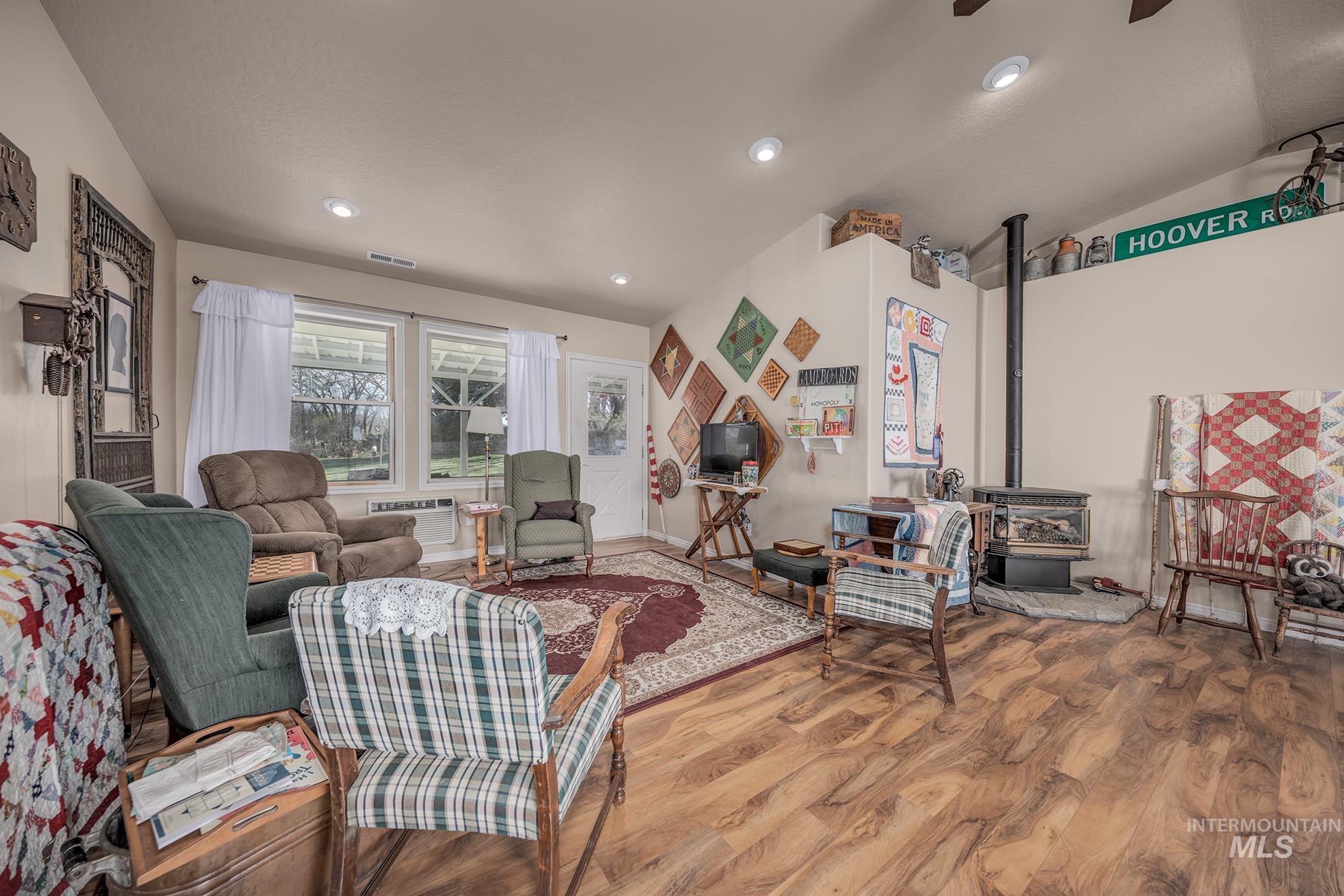1365 Highway 95 Weiser, ID 83672 - Photo 9 of 34 Living area featuring a wood stove, wood finished floors, ceiling fan, lofted ceiling, and recessed lighting