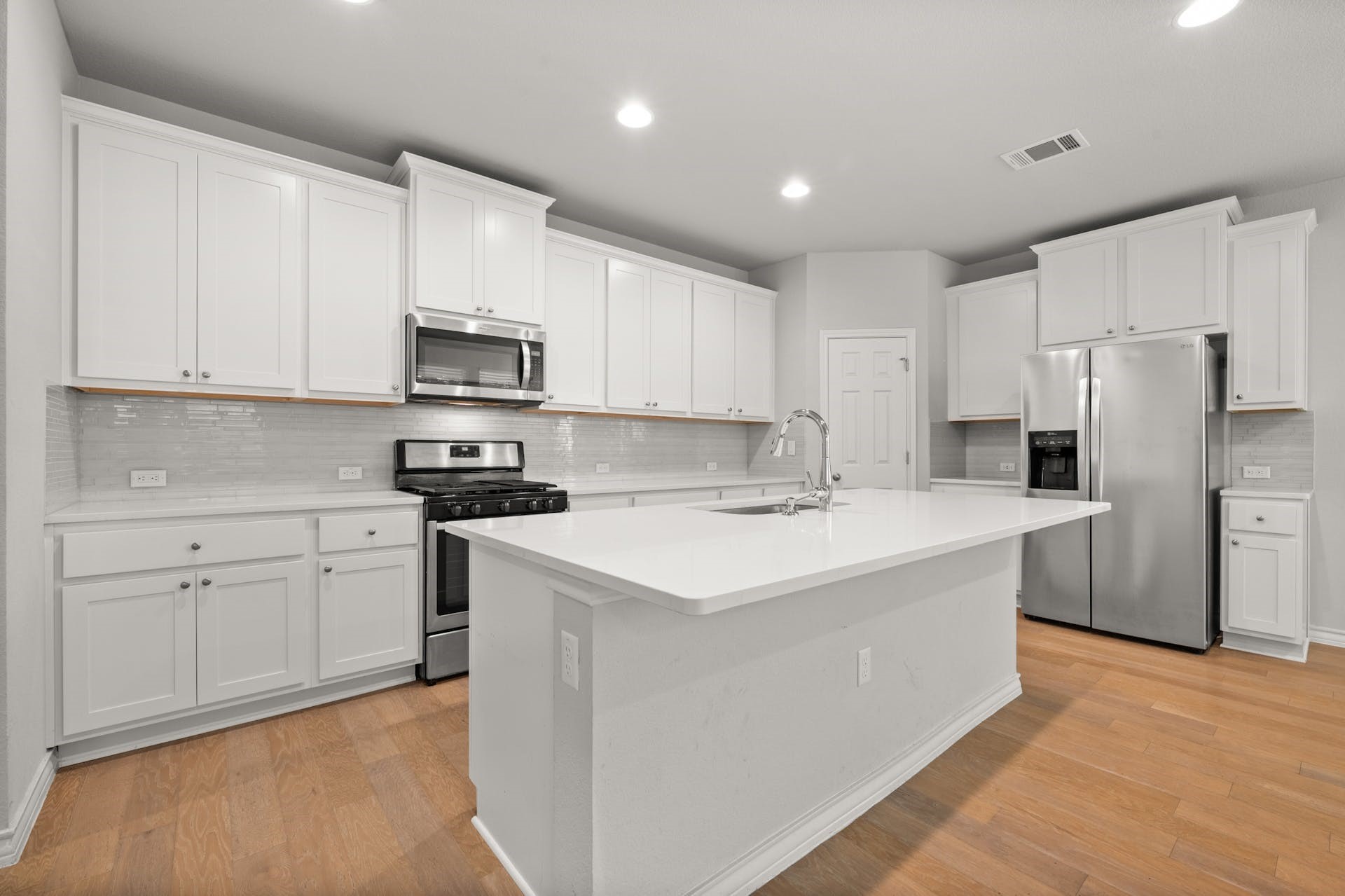 5107 Lemon Tree Path, Unit 127 Austin, TX 78723 - Photo 6 of 40 a kitchen with stainless steel appliances granite countertop a sink stove refrigerator and white cabinets with wooden floor