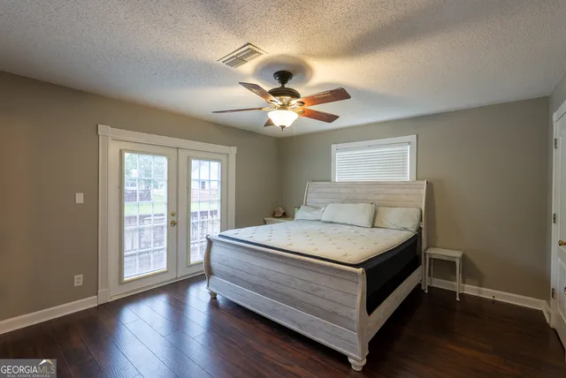 a bedroom with a bed and a large window with wooden floor