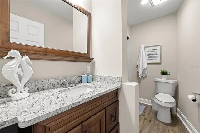 a bathroom with a granite countertop sink and a toilet