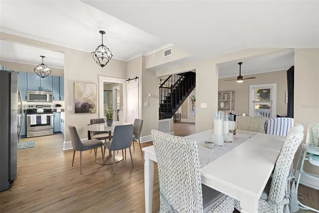 a dining room with wooden floor a chandelier a wooden table and chairs