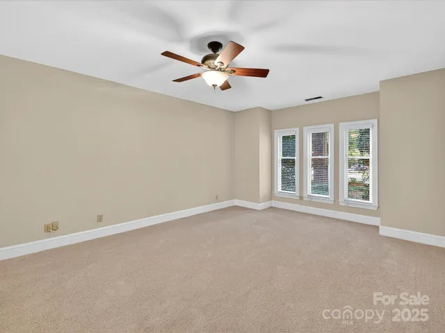 an empty room with windows and ceiling fan