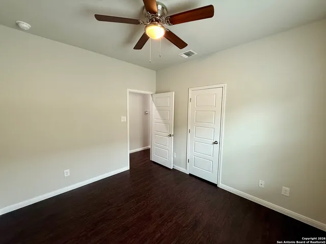 an empty room with wooden floor and a ceiling fan