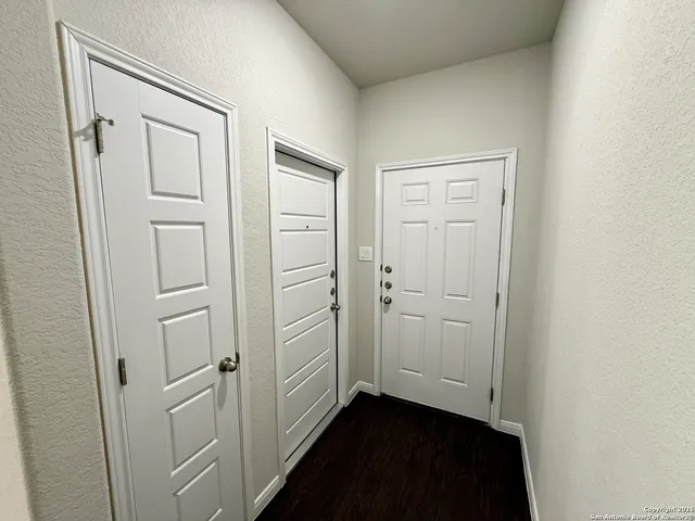 an empty room with wooden floor cabinet and door