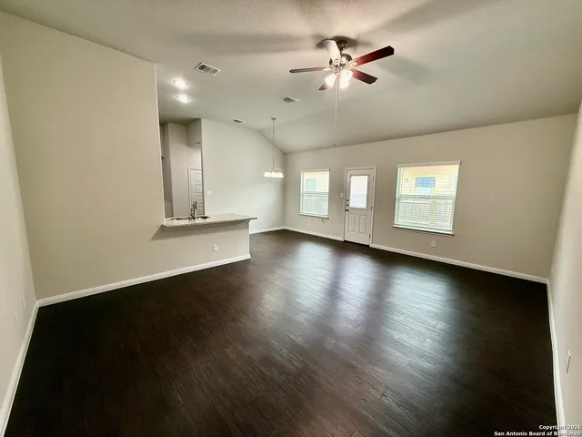 a view of an empty room with a window and wooden floor