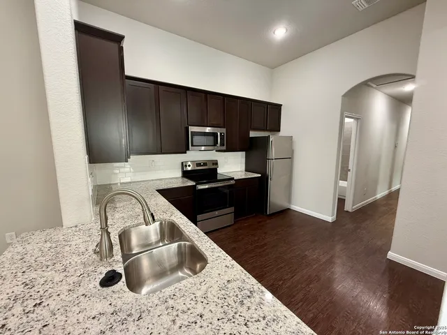 a kitchen with a sink a refrigerator and a stove top oven
