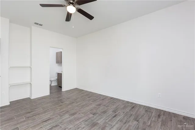 a view of empty room with wooden floor and ceiling fan