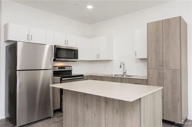 a kitchen with stainless steel appliances a refrigerator a sink a stove a microwave and island