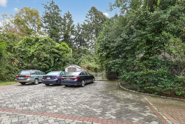 a front view of a house with cars parked on road