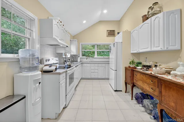 a kitchen with stainless steel appliances a sink a stove a refrigerator cabinets and a window