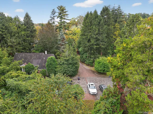 an aerial view of a house with a yard and trees all around