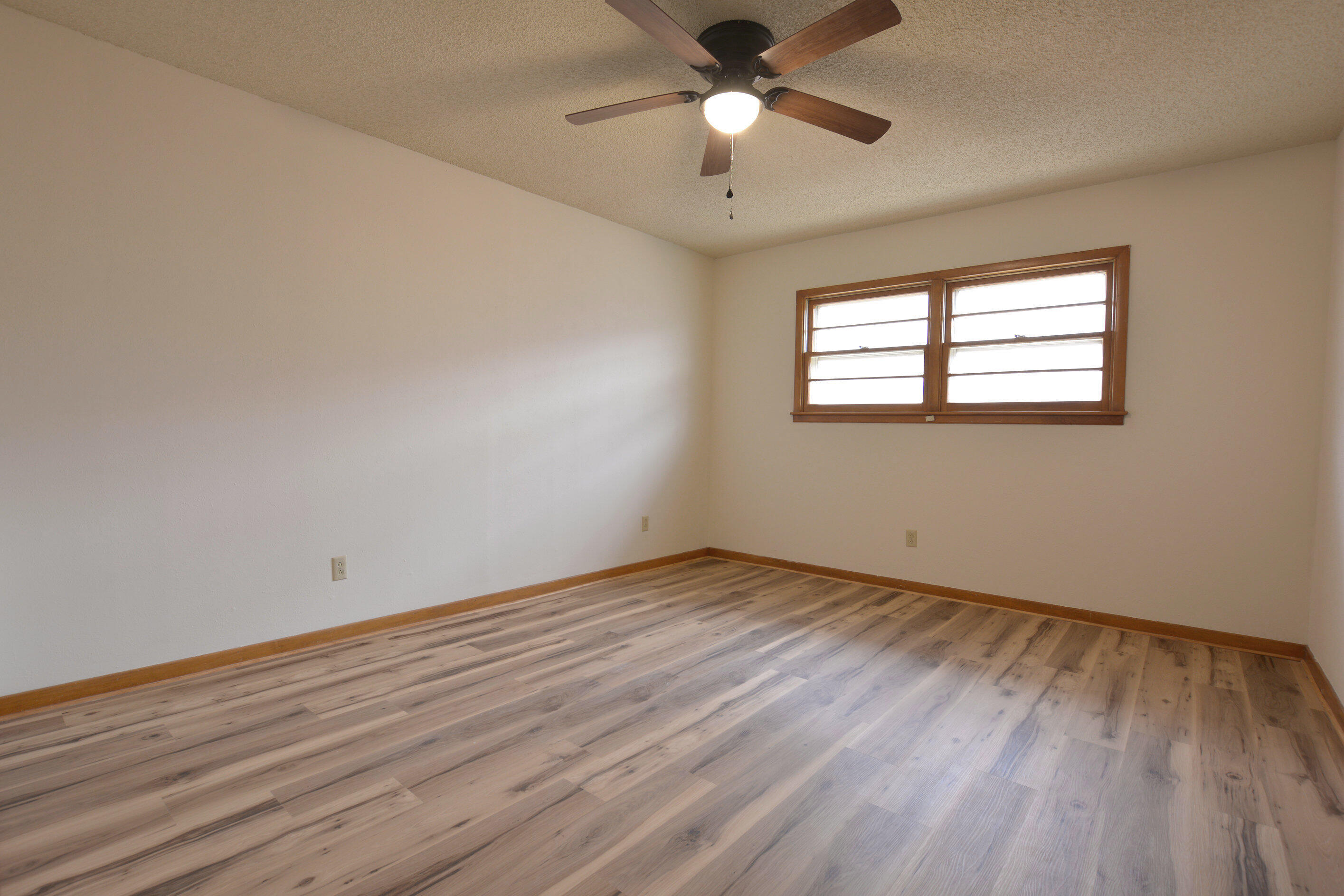 5224 9th Street Lubbock, TX 79416 - Photo 19 of 26 an empty room with wooden floor chandelier fan and windows