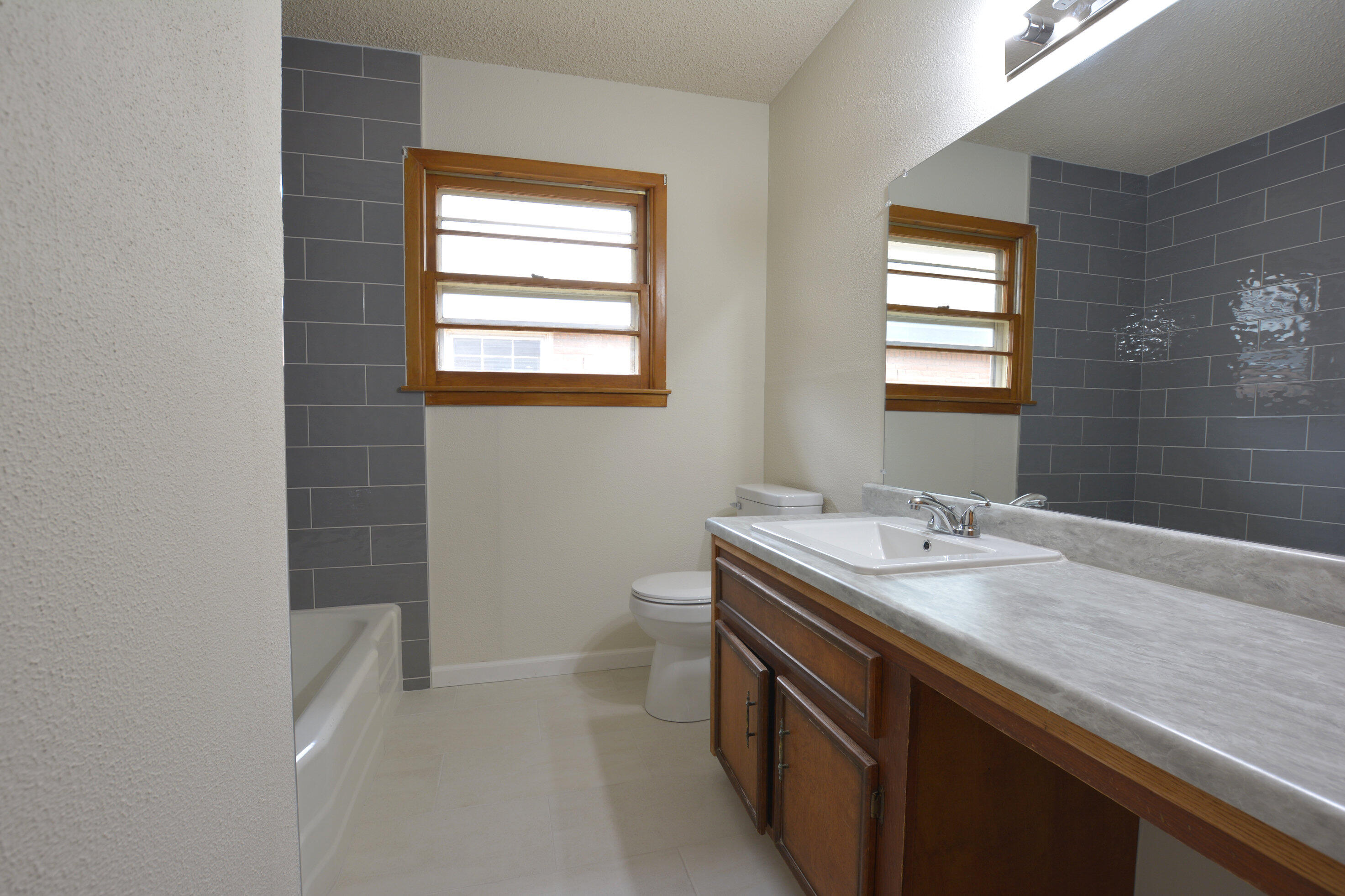 5224 9th Street Lubbock, TX 79416 - Photo 21 of 26 a bathroom with a granite countertop sink a mirror and a bathtub