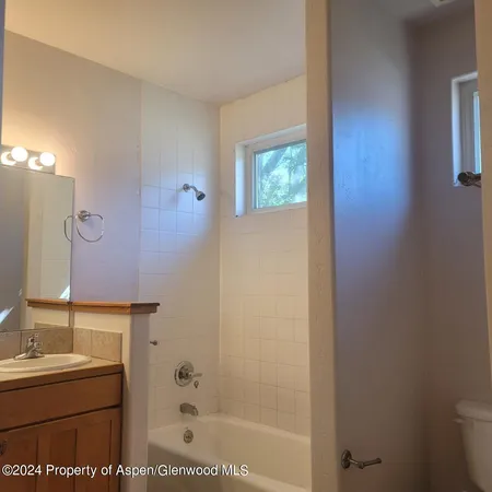 a bathroom with a granite countertop sink a toilet and a bathtub
