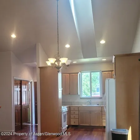 a kitchen with stainless steel appliances a refrigerator a sink a microwave a dining table and chairs