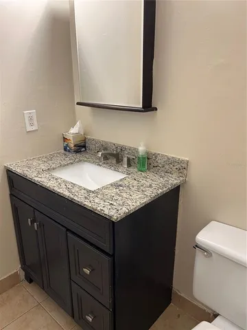 a bathroom with a granite countertop sink and a toilet