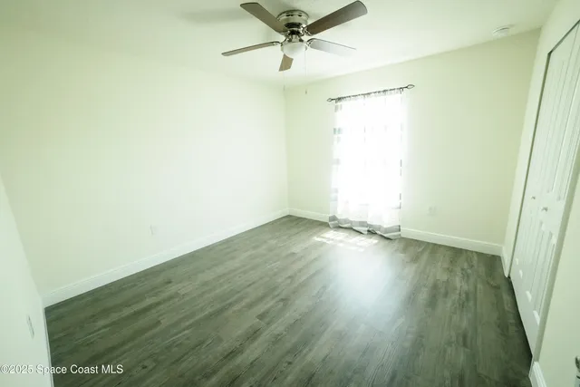 a view of a room with wooden floor and a ceiling fan