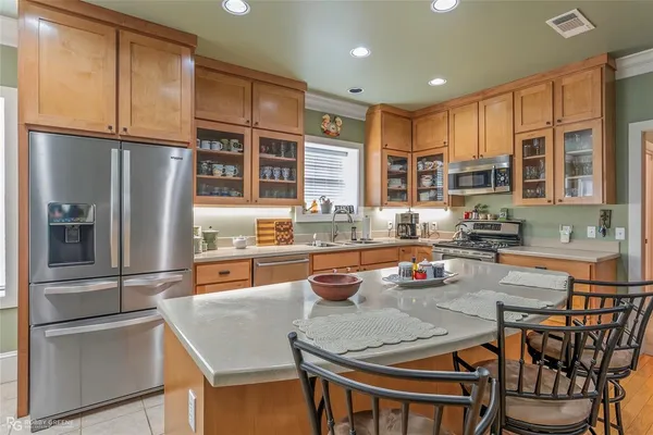 a kitchen with stainless steel appliances granite countertop a refrigerator a stove a sink and a dining table