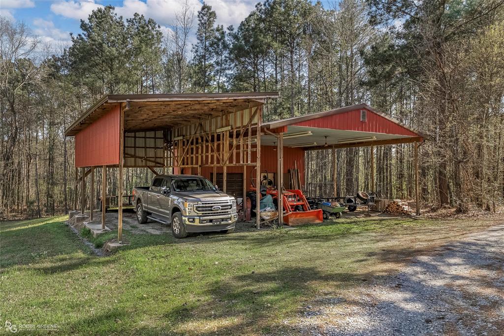 6340 Pine Hill Road Shreveport, LA 71107 - Photo 9 of 40 View of car parking featuring an outbuilding, driveway, and a forest view