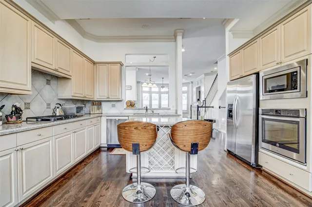a kitchen with stainless steel appliances kitchen island granite countertop a stove a sink a dining table and chairs