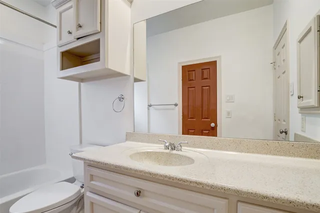 a bathroom with a granite countertop sink a toilet and mirror