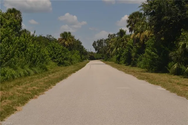 a view of a lake with a yard and trees in the background