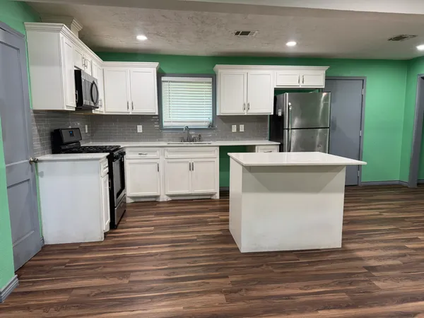 a kitchen with stainless steel appliances granite countertop a refrigerator sink and white cabinets