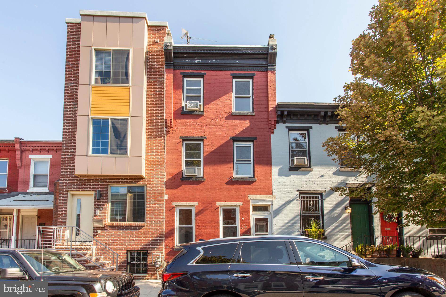 a front view of a building with lot of cars and trees