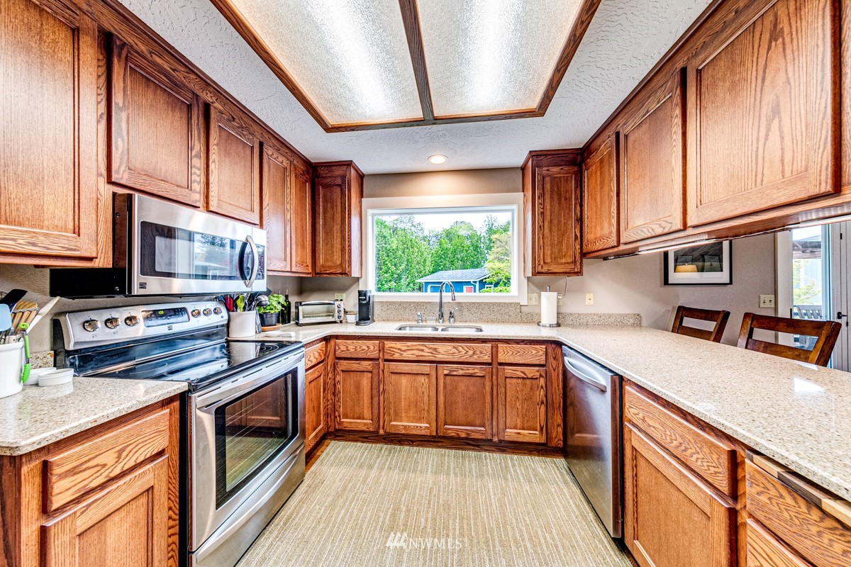 173 View Ridge Drive Port Angeles, WA 98362 - Photo 8 of 27 a kitchen with stainless steel appliances granite countertop wooden cabinets a sink and dishwasher a stove top oven with wooden floor