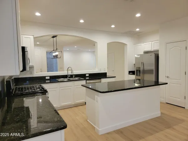 a large kitchen with stainless steel appliances a large counter top a stove and a refrigerator